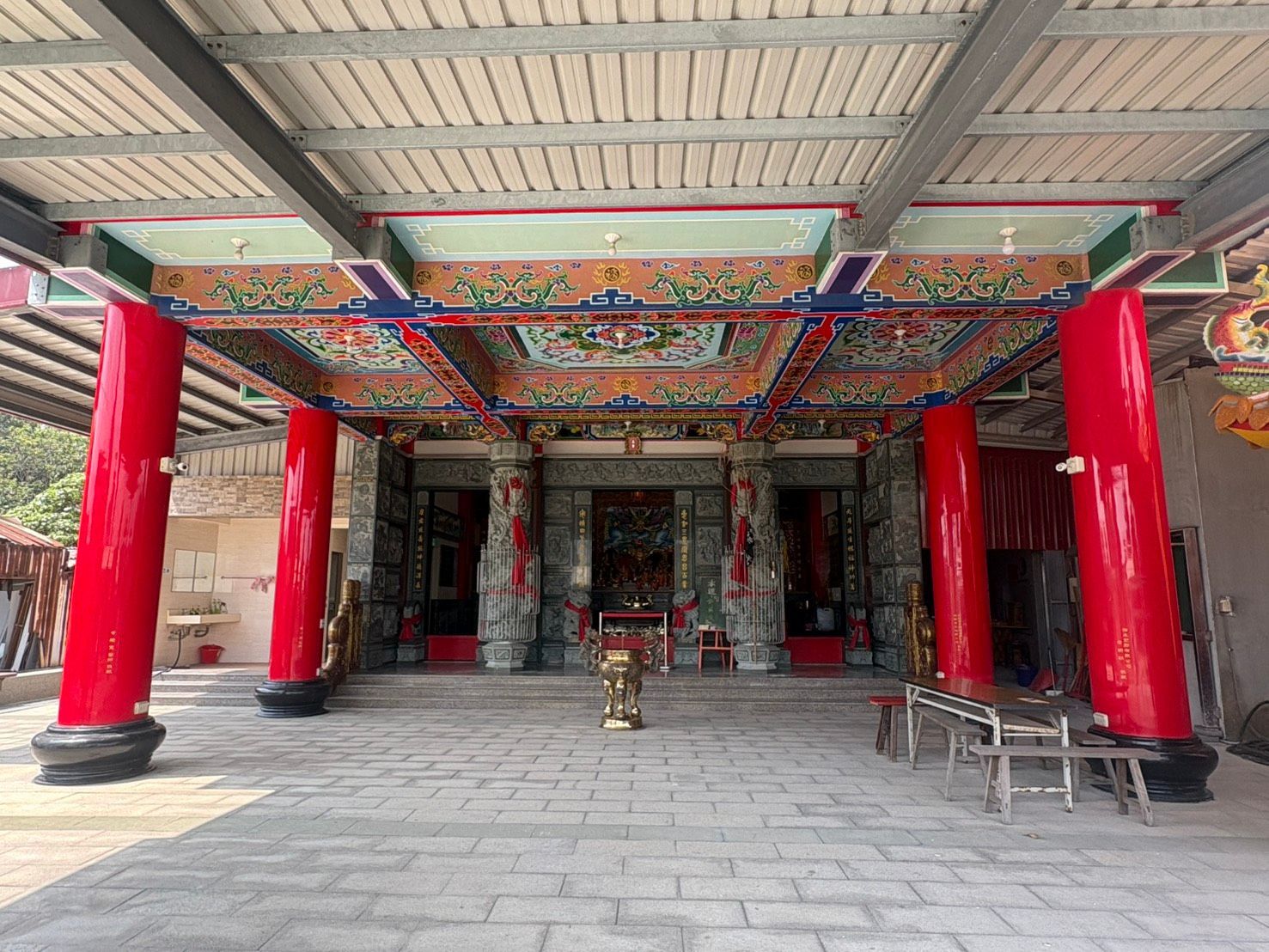 寺廟內部有紅色立柱、裝飾華麗的彩繪天花板和石頭地板。
