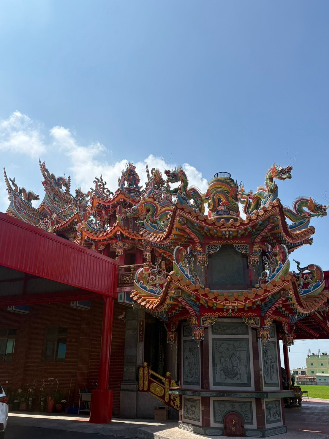 藍天下,一座紅色建築旁,色彩繽紛的中國寺廟屋頂上雕刻著精美的龍紋。