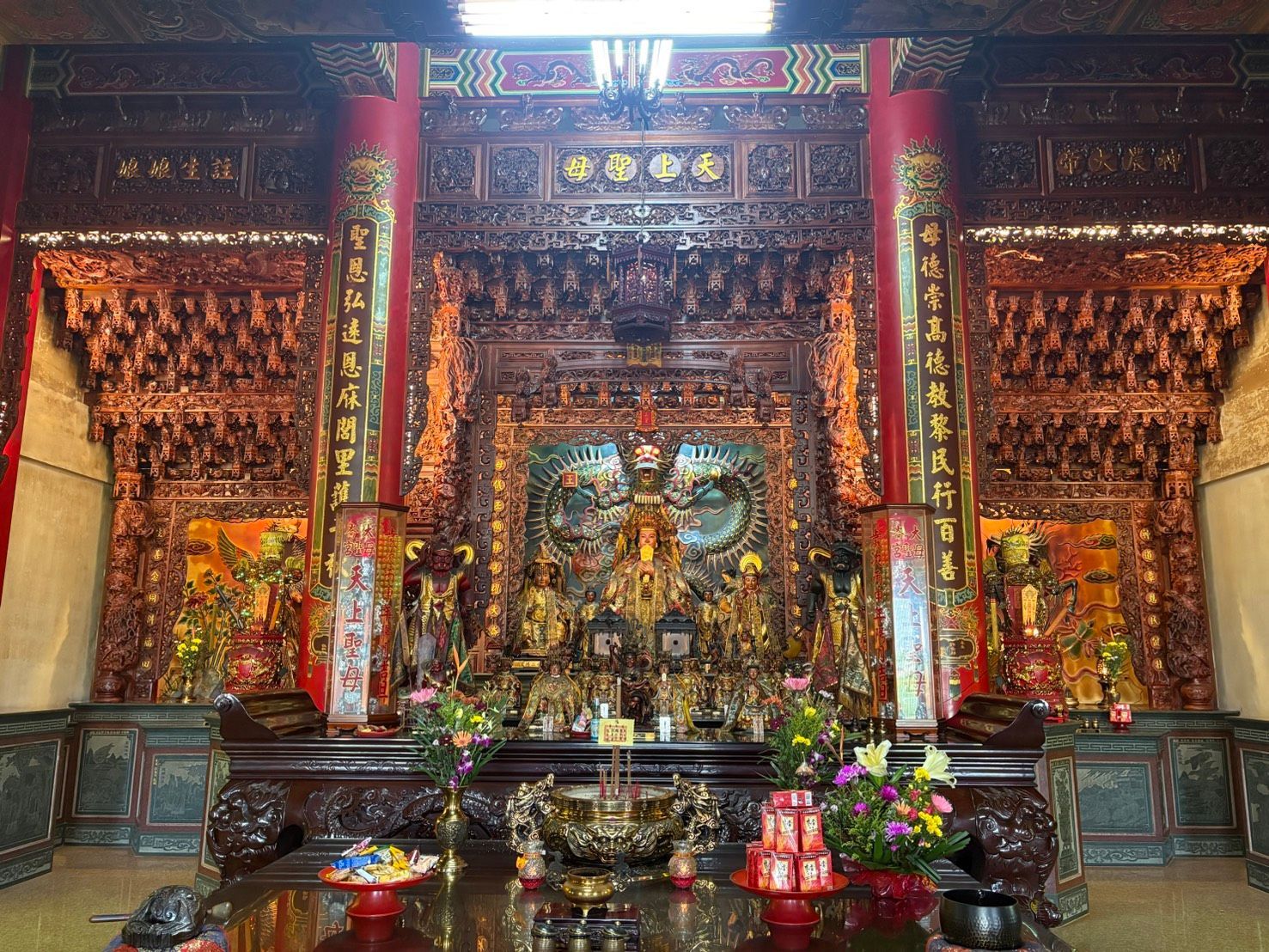 裝飾華麗的寺廟祭壇,擺放著金色的雕像、紅色的柱子和供品,位於一個裝飾精美的神龕中。