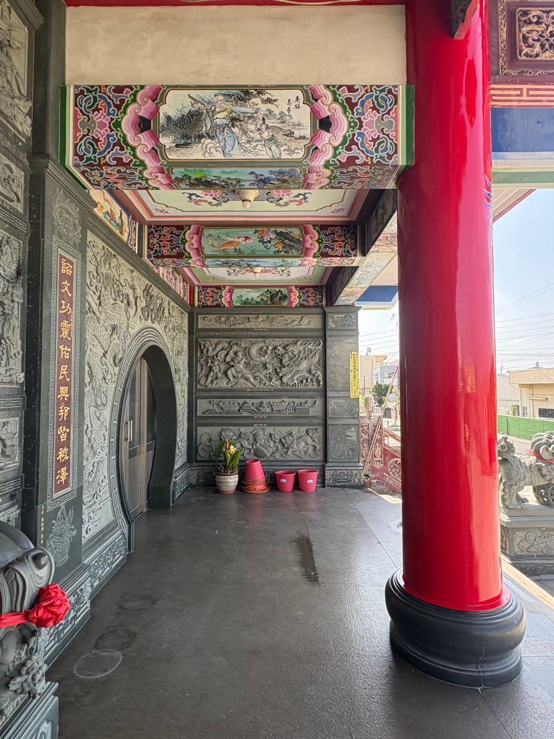 寺廟走廊,天花板彩繪華麗,紅色立柱,石頭地面上裝飾著精美的牆板。
