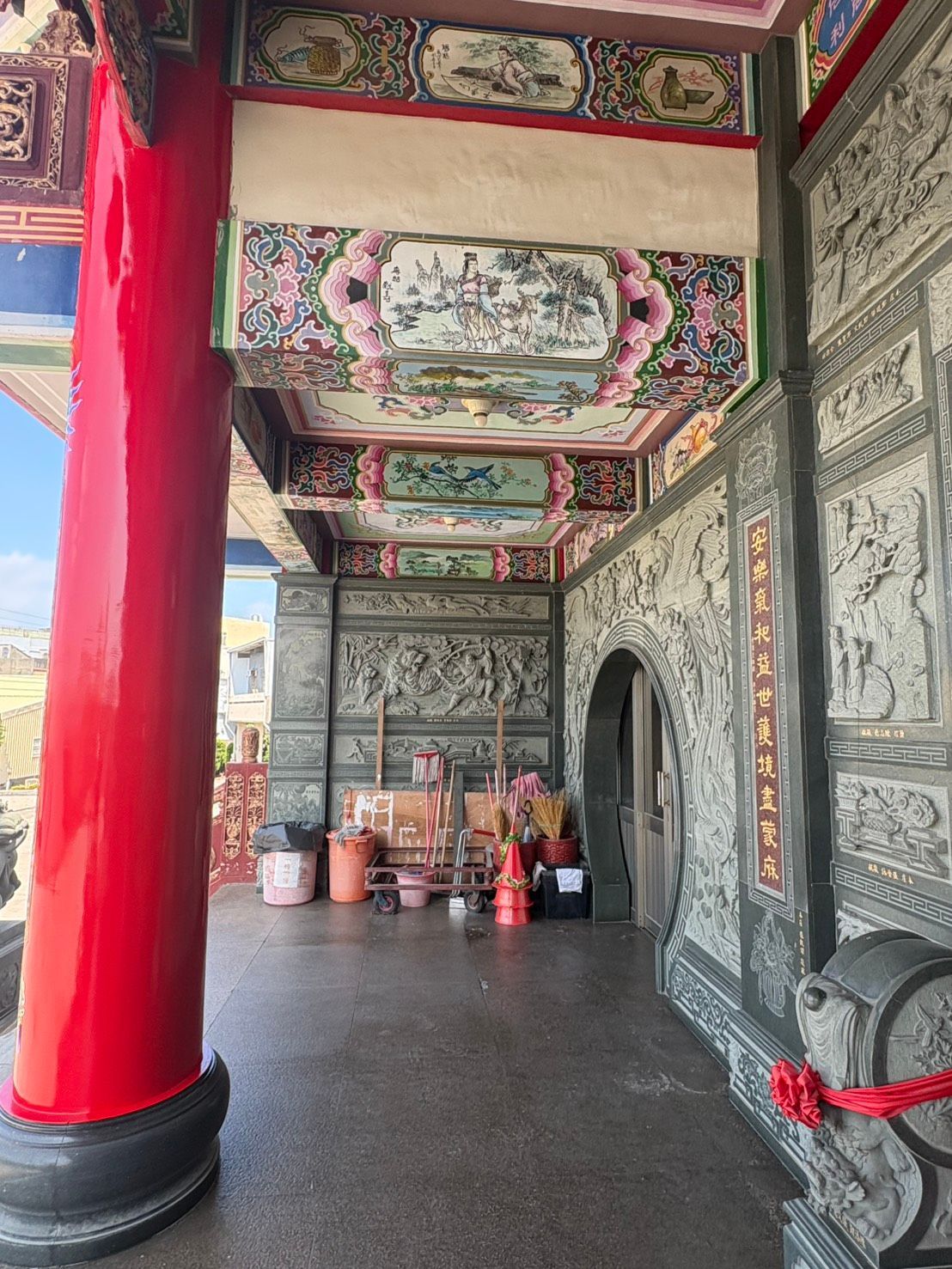 華麗的寺廟走廊,兩側是紅色的柱子、雕刻精美的天花板,牆上擺放著供品。