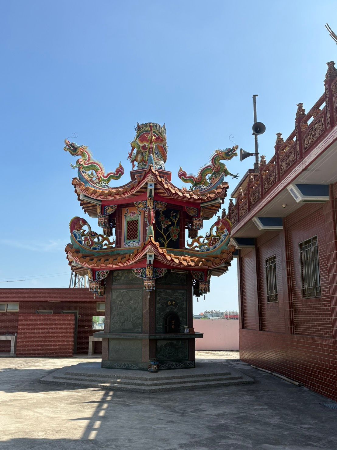 在湛藍的天空下,一座紅磚建築旁矗立著一座小巧精緻的中式寺廟亭台樓閣。