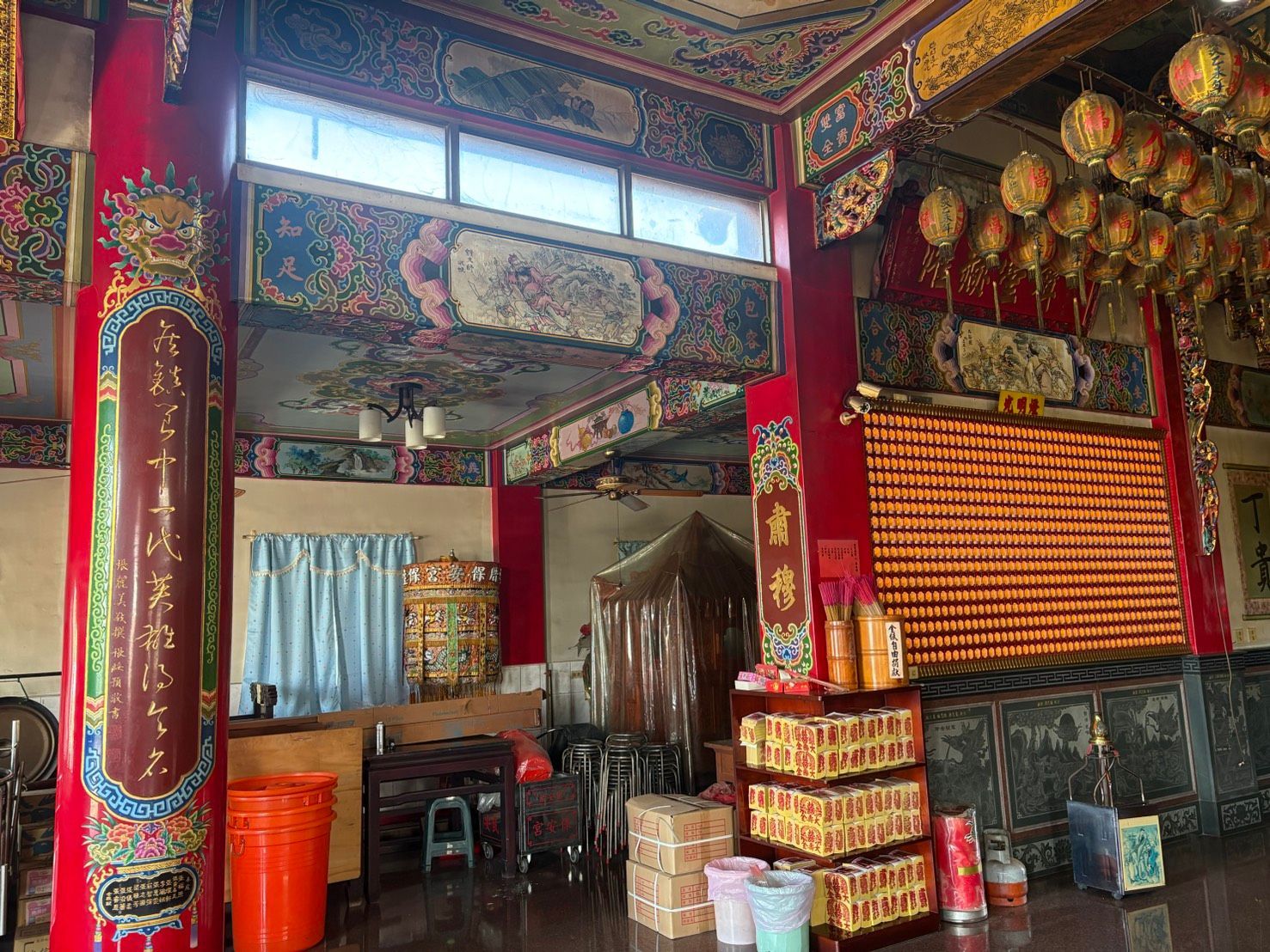 寺廟內部裝飾華麗,有紅色的柱子、懸掛的燈籠,以及圍繞著小型祭壇區域的椅子。
