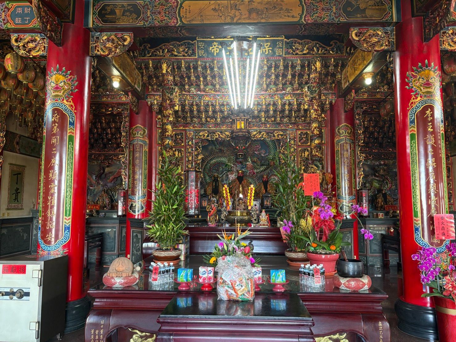 廟內,裝飾華麗的祭壇,紅色的柱子,金色的裝飾,以及供奉的祭品。