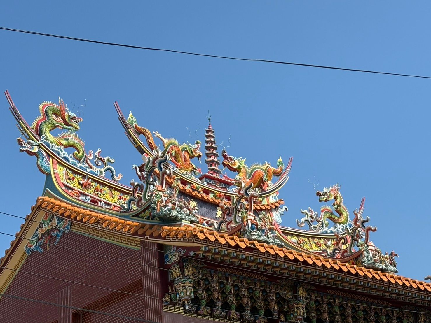 華麗的寺廟屋頂上雕刻著色彩斑斕的龍鳳圖案,映襯著蔚藍的天空。