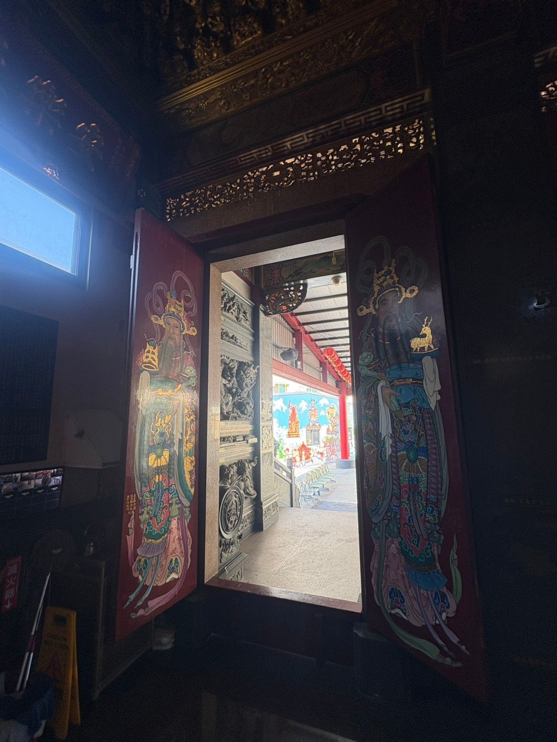 華麗的寺廟大門通往明亮的庭院,庭院內有色彩鮮豔的彩繪鑲板和精美的雕刻細節。