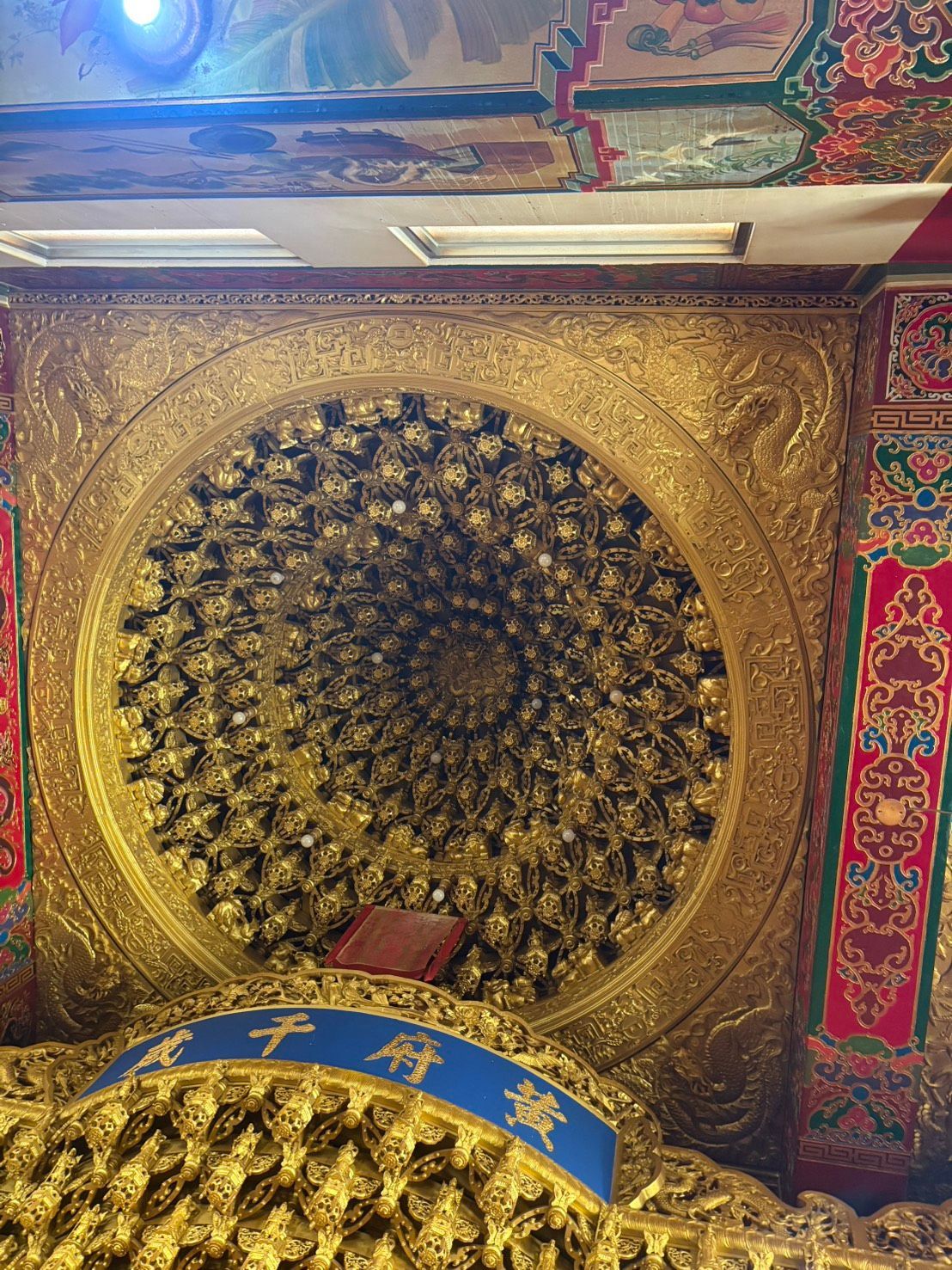金色華麗的天花板上飾有圓形花卉圖案,藍色拱門上方是色彩繽紛的裝飾板。拱門上方是華麗的金色天花板,天花板上還有彩色裝飾板。