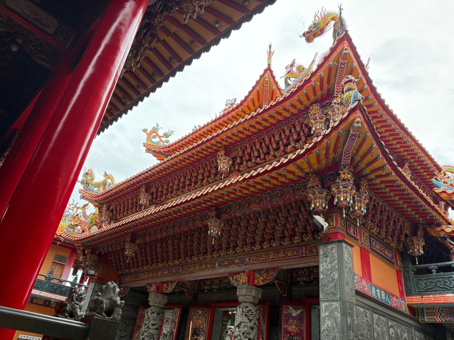 從低角度拍攝的華麗紅金相間的寺廟,其屋簷和柱子都雕刻精美。