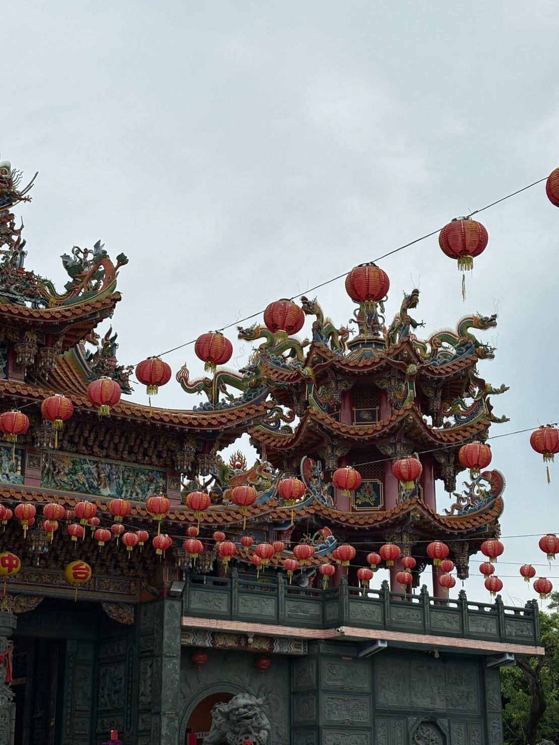 在陰雲密佈的天空下,傳統中國寺廟的屋頂上掛滿了紅燈籠。