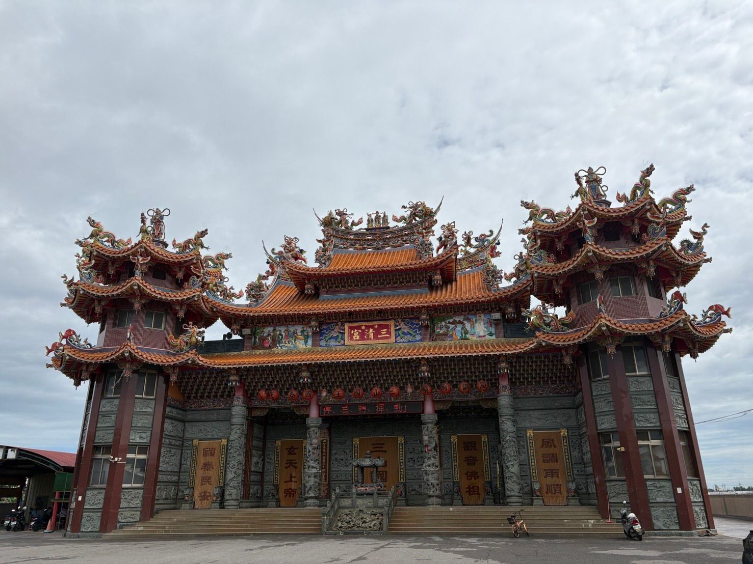 雲層下,一座裝飾華麗的傳統中國寺廟,屋頂以紅色和金色點綴。