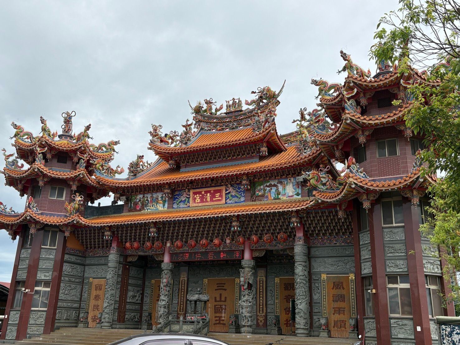 華麗的傳統中國寺廟立面,有紅色的柱子、雕刻的細節和層疊的屋簷。