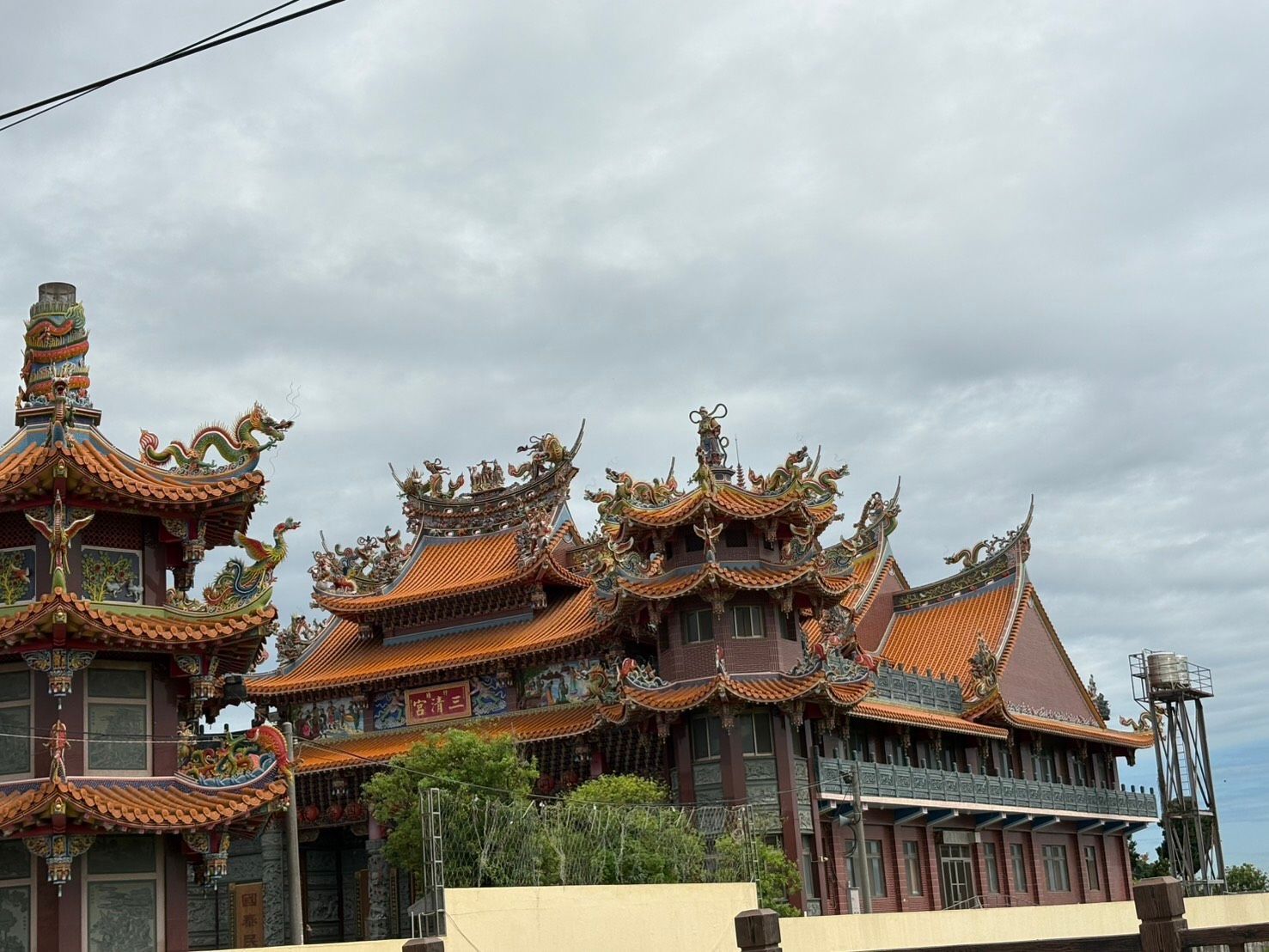 在陰雲密佈的天空下,一座裝飾華麗的亞洲寺廟,紅瓦金邊,氣勢恢宏。