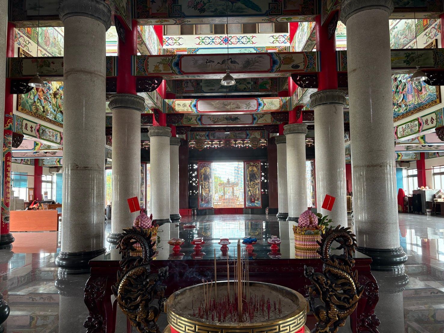華麗的寺廟大殿,有高聳的柱子、色彩繽紛的天花板橫樑和中央的香爐。