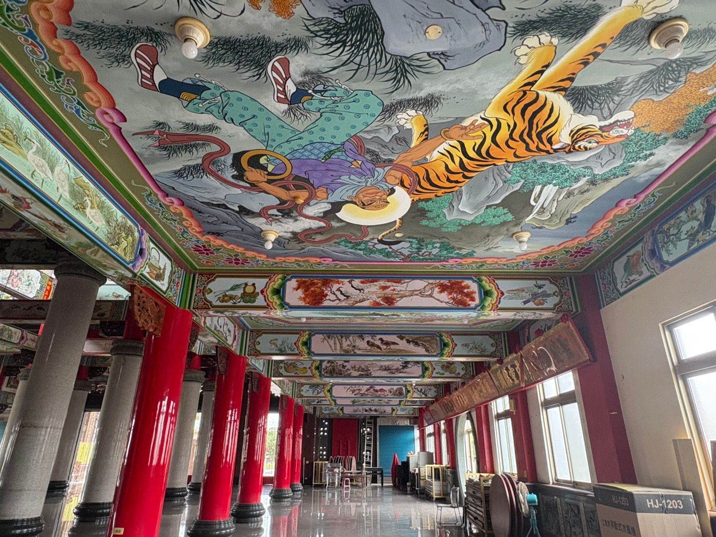 裝飾華麗的寺廟大殿,天花板上繪有栩栩如生的龍形壁畫,配上紅色立柱和兩側的窗戶。