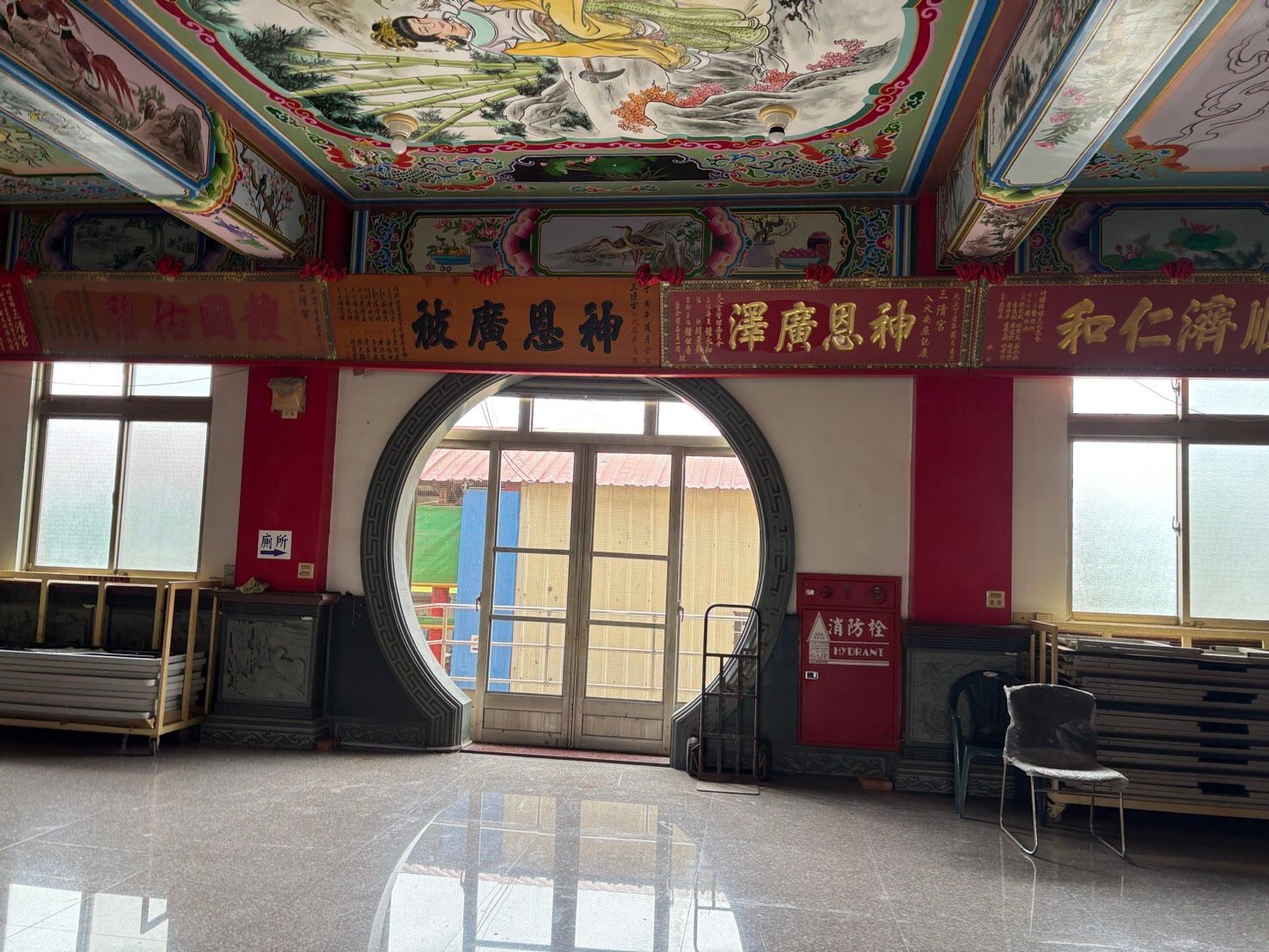 寺廟內部裝潢華麗,有紅色立柱、中國書法作品,以及通往庭院的圓形門。