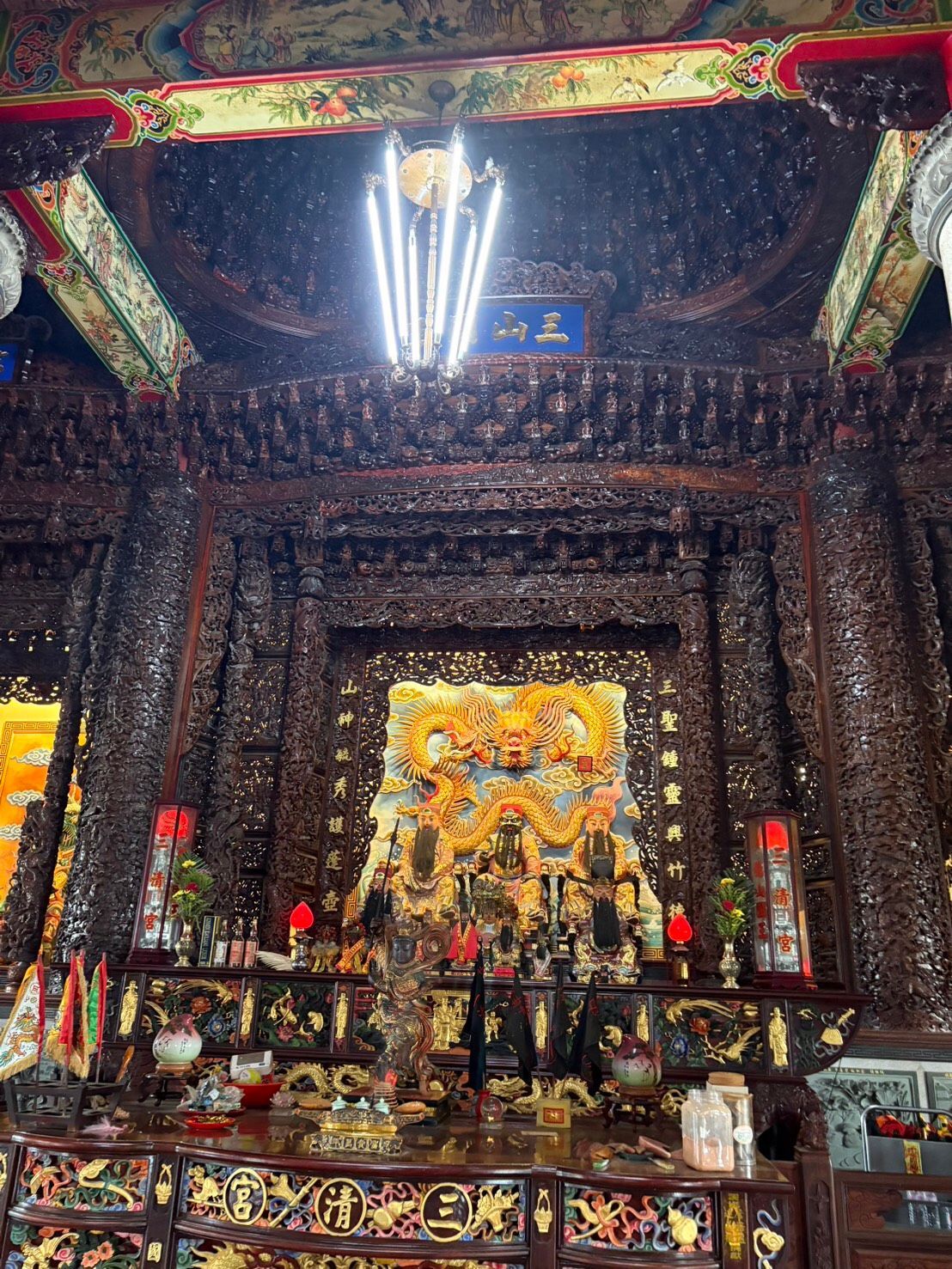 在裝飾華麗的寺廟祭壇上,金色的雕像、紅色的燈籠和色彩繽紛的雕花橫樑在明亮的吊燈下閃閃發光。