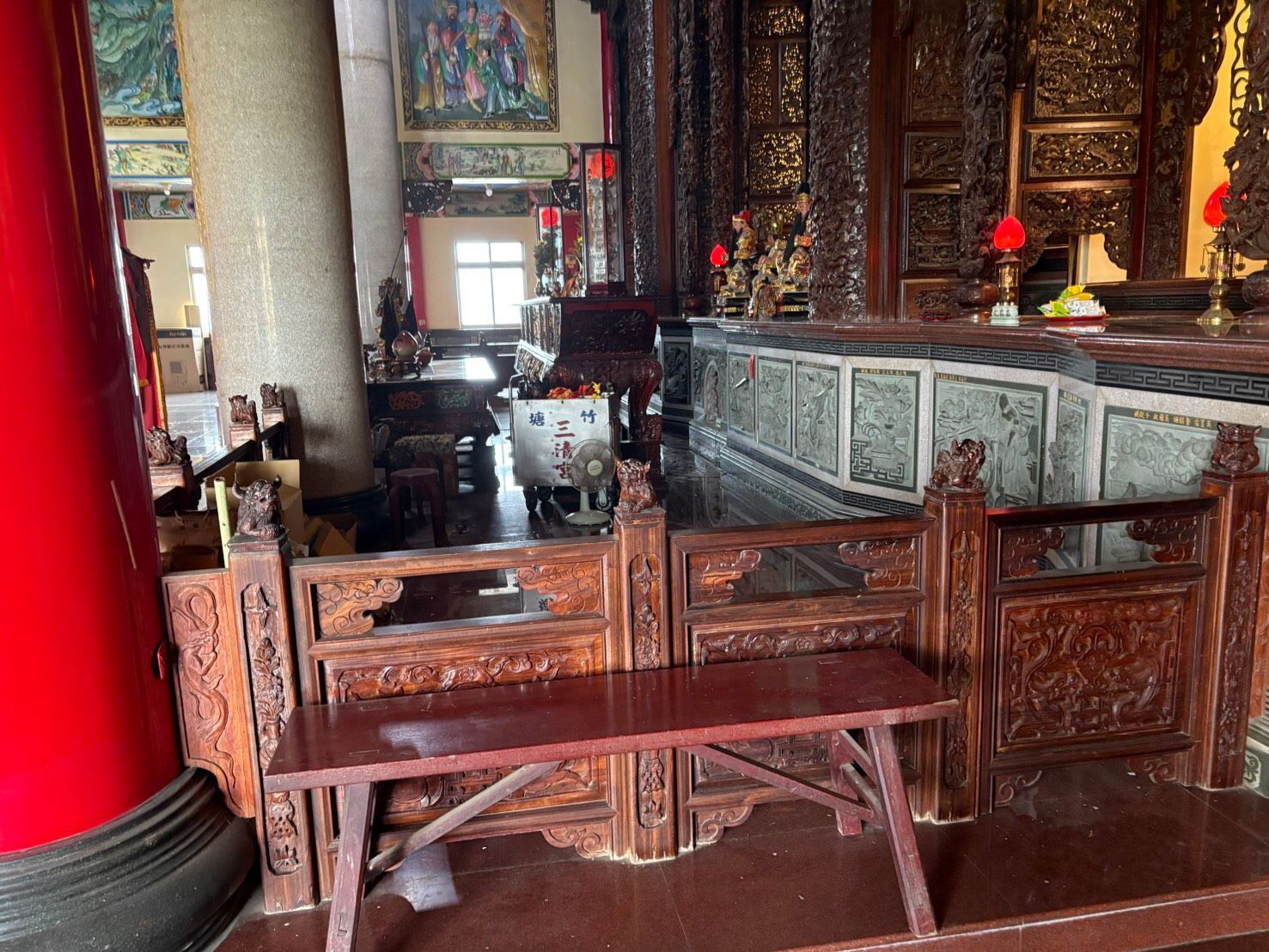 寺廟內部裝飾華麗,配有木製長凳、雕刻精美的柱子和紅色石柱。