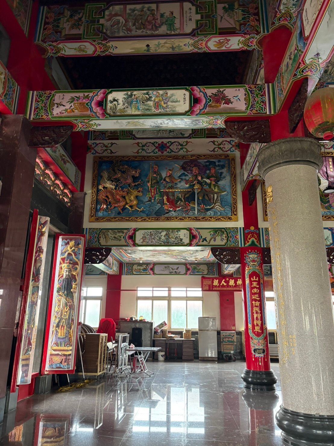寺廟內部裝飾華麗,有紅色的柱子、彩繪的天花板和光亮的瓷磚地板。