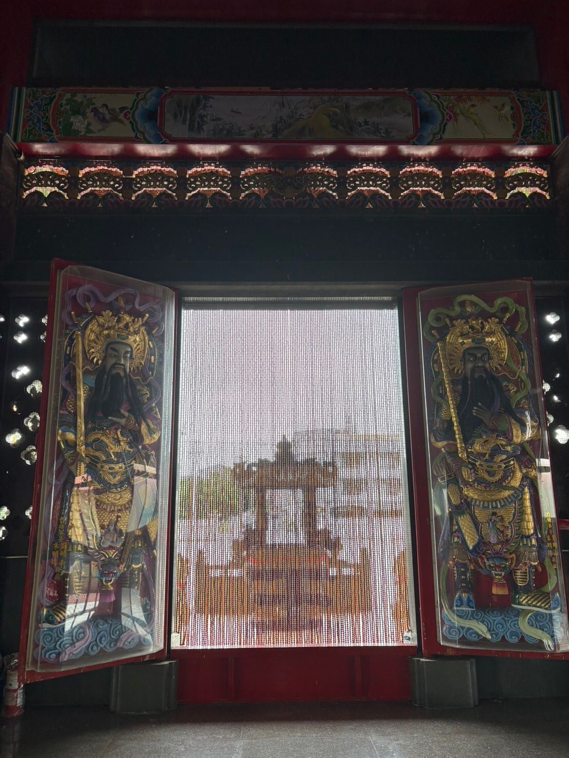 寺廟壁龕內,敞開的神龕大門上鑲嵌著彩繪鑲板,框出一幅色彩鮮豔、圖案精美的帷幔。