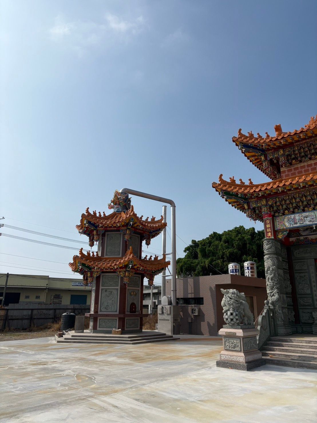 陽光灑滿寺廟庭院,橙色屋頂的華麗大門和石柱矗立在湛藍的天空下。