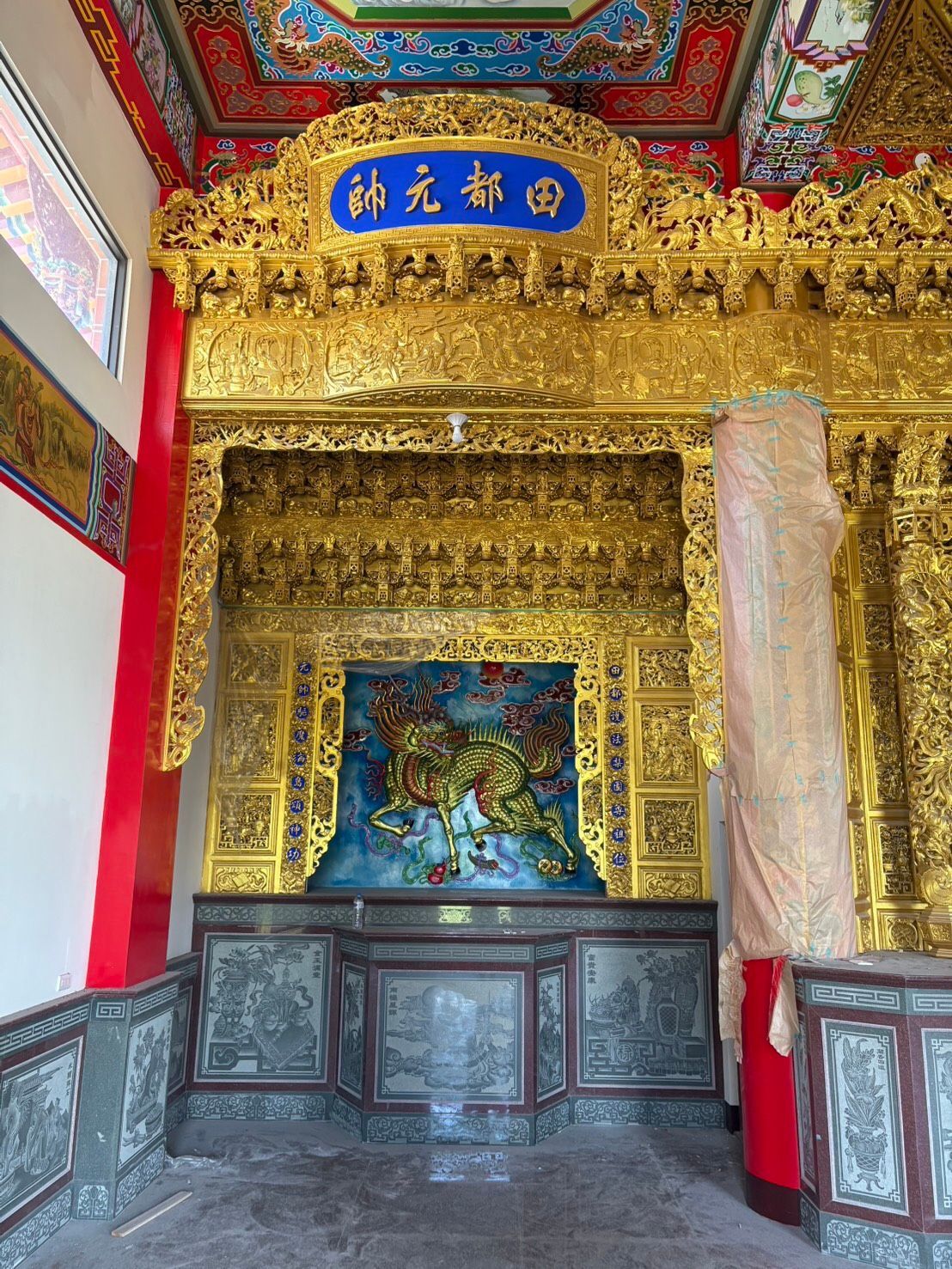 華麗的中國式寺廟內部裝飾精美,飾有金雕、藍色匾額和中央祭壇壁龕。