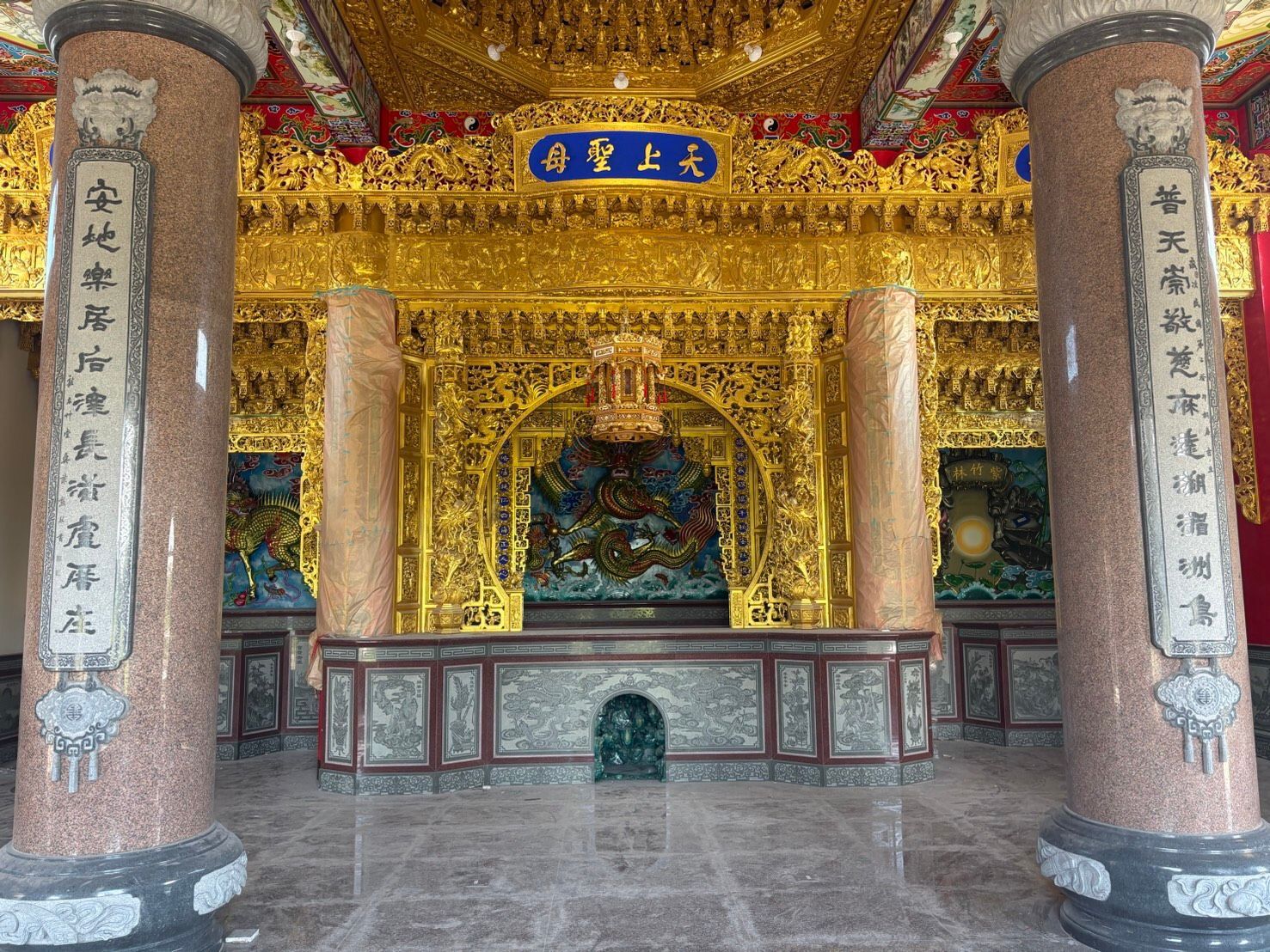 裝飾華麗的寺廟大殿,配有金色祭壇、紅色石柱和雕刻精美的天花板裝飾。