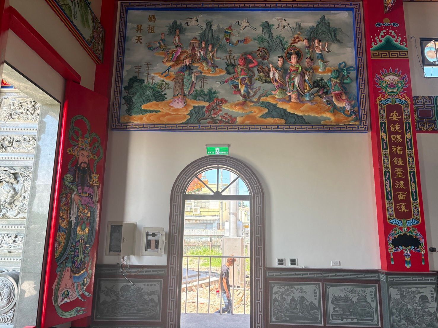 裝飾華麗的寺廟入口,飾有精美的壁畫、紅色的柱子,以及一扇通往明亮日光的門。