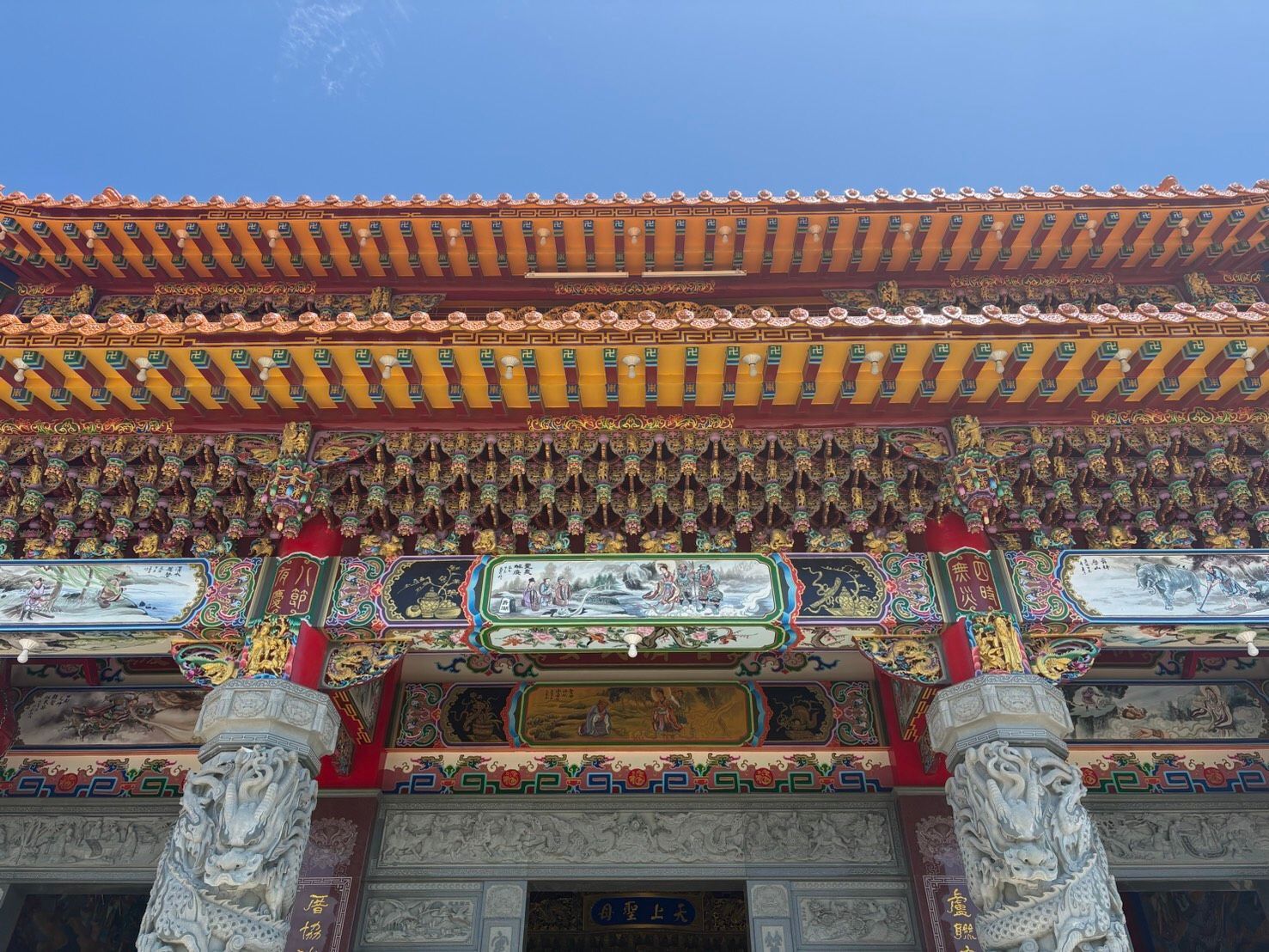 華麗的寺廟立面,飾有雕刻精美的石柱、色彩斑斕的彩繪屋簷和傳統的亞洲屋頂細節。