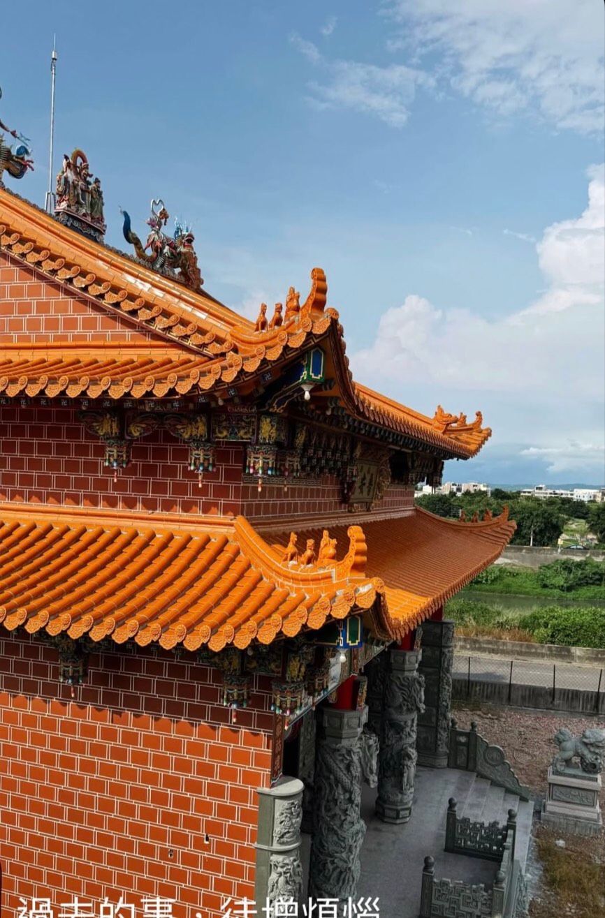 藍天下,一座傳統的中國寺廟,橙色的瓦頂和磚牆,俯瞰鄉村景色。