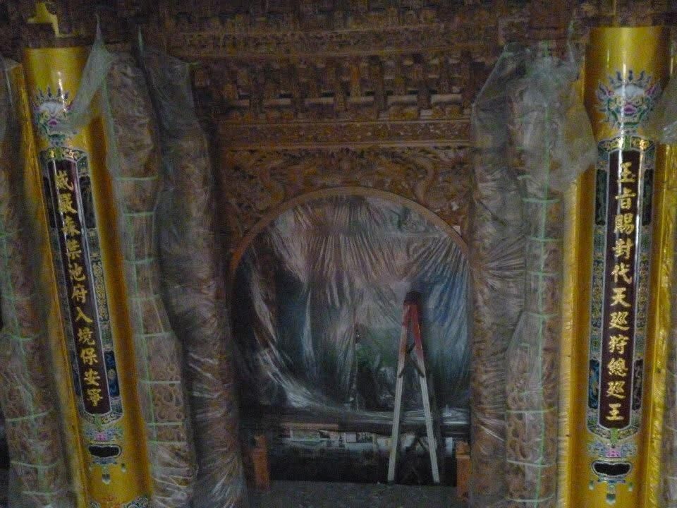 裝飾華麗的寺廟神龕,帶有精美的雕刻拱門、懸掛的幡旗,以及中央的彩繪場景或祭壇區域。