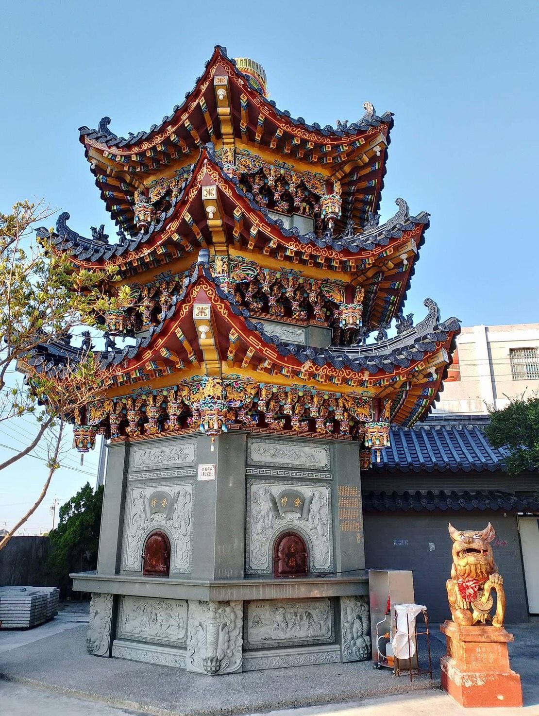 華麗的多層中國式寺廟亭台樓閣,紅金相間的屋簷,入口處有一尊獅子像。