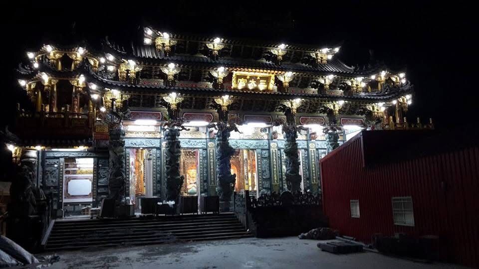 夜幕降臨,燈火輝煌的華麗寺廟映入眼簾,寺廟旁有階梯和一座紅色建築。