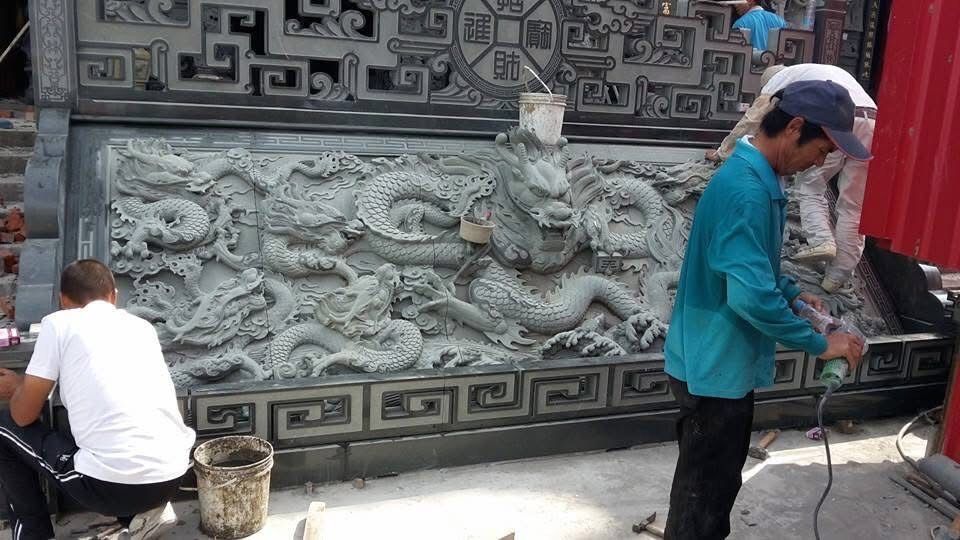 工人們正在紅牆和華麗大門旁雕刻一塊大型石浮雕。