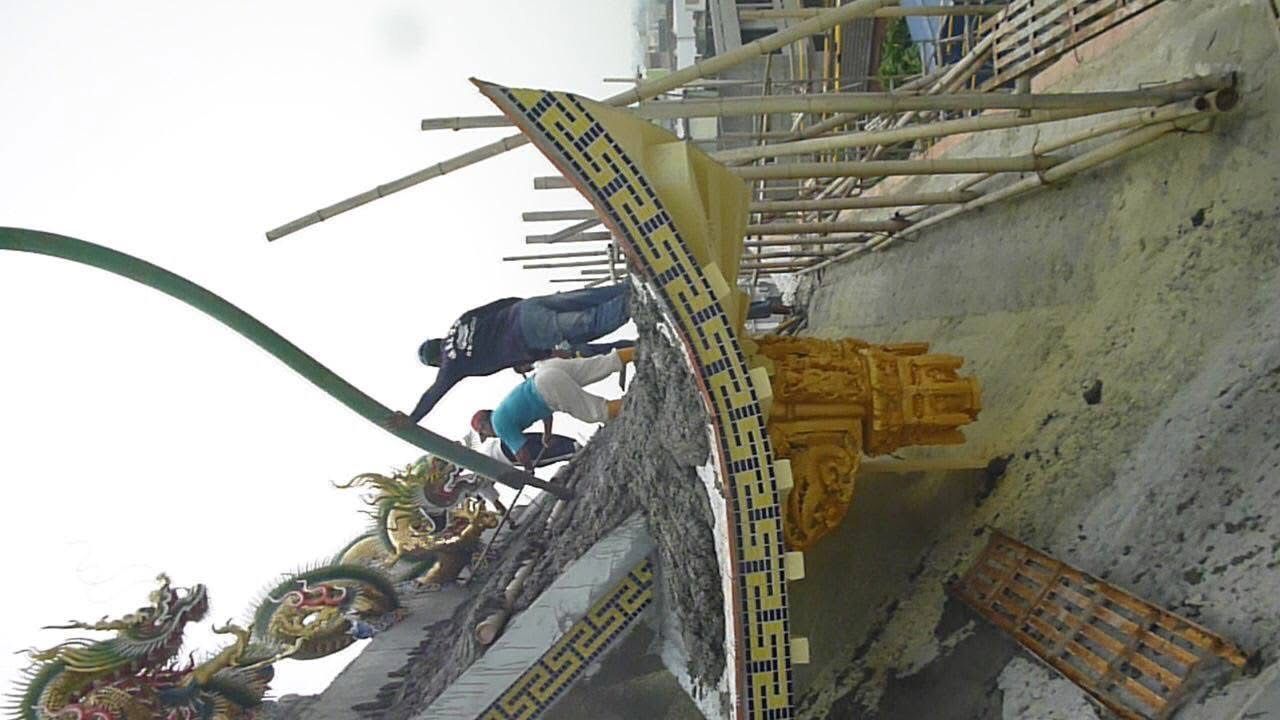 工人們在建築工地的混凝土模板上作業,周圍有竹製鷹架和黃色警戒線。