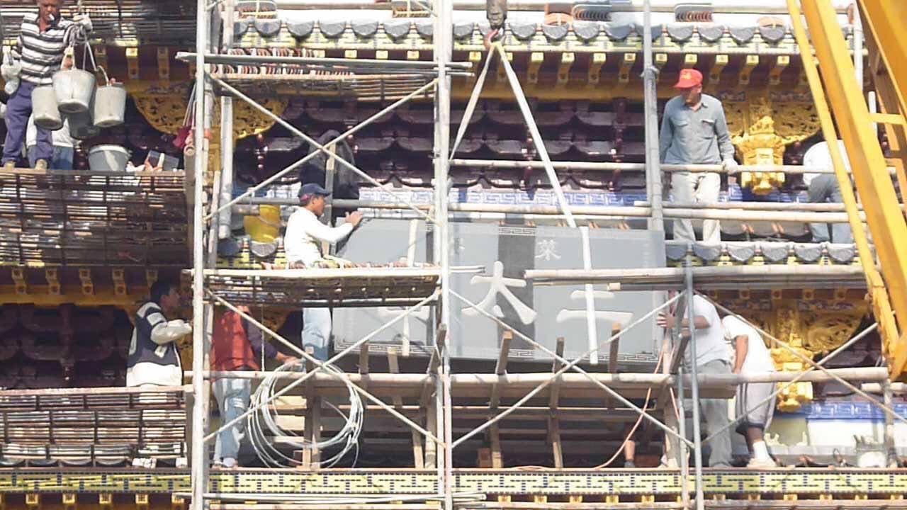 工人在大型雕像周圍的鷹架上作業,鷹架上擺放著金屬樑和建築材料。