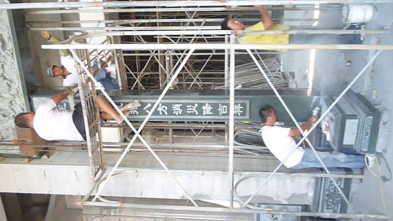 工人們在建築物內的金屬鷹架上安裝或修理牆面標誌。