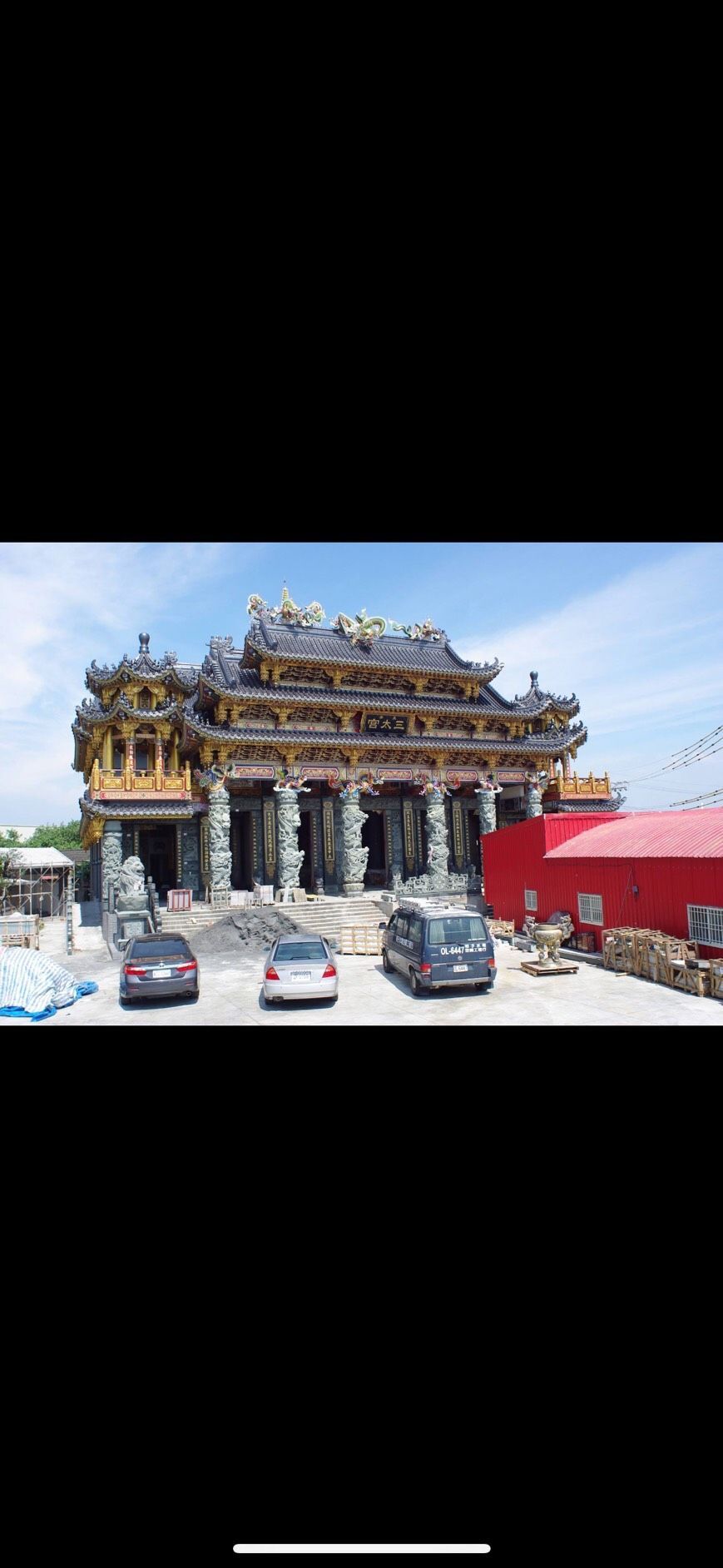 華麗的印度教寺廟,雕花塔樓,紅色華蓋,晴空下停放摩托車。