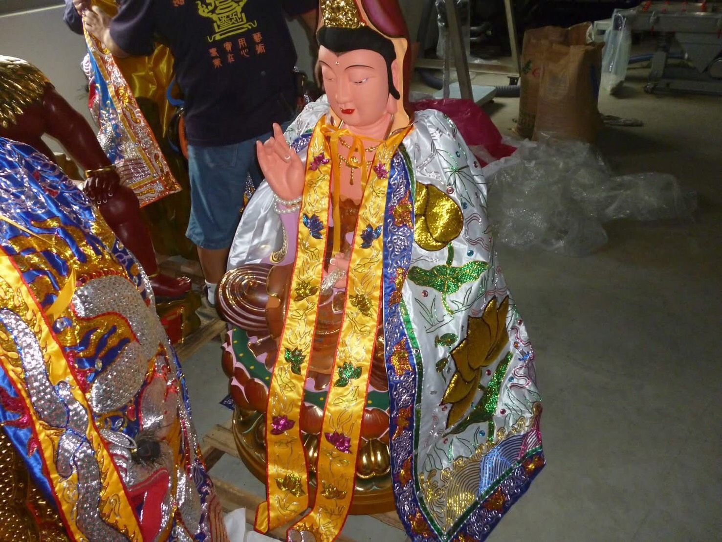 身著華麗金銀禮服的人,站在室內,周圍環繞著色彩繽紛的裝飾。