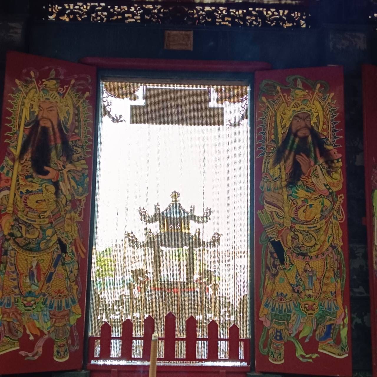 華麗的寺廟大門,飾有紅色和金色的守護神壁畫,並掛著珠簾。