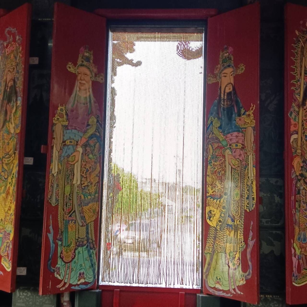紅色神龕門,懸掛著珠簾,兩側繪有守護神像。