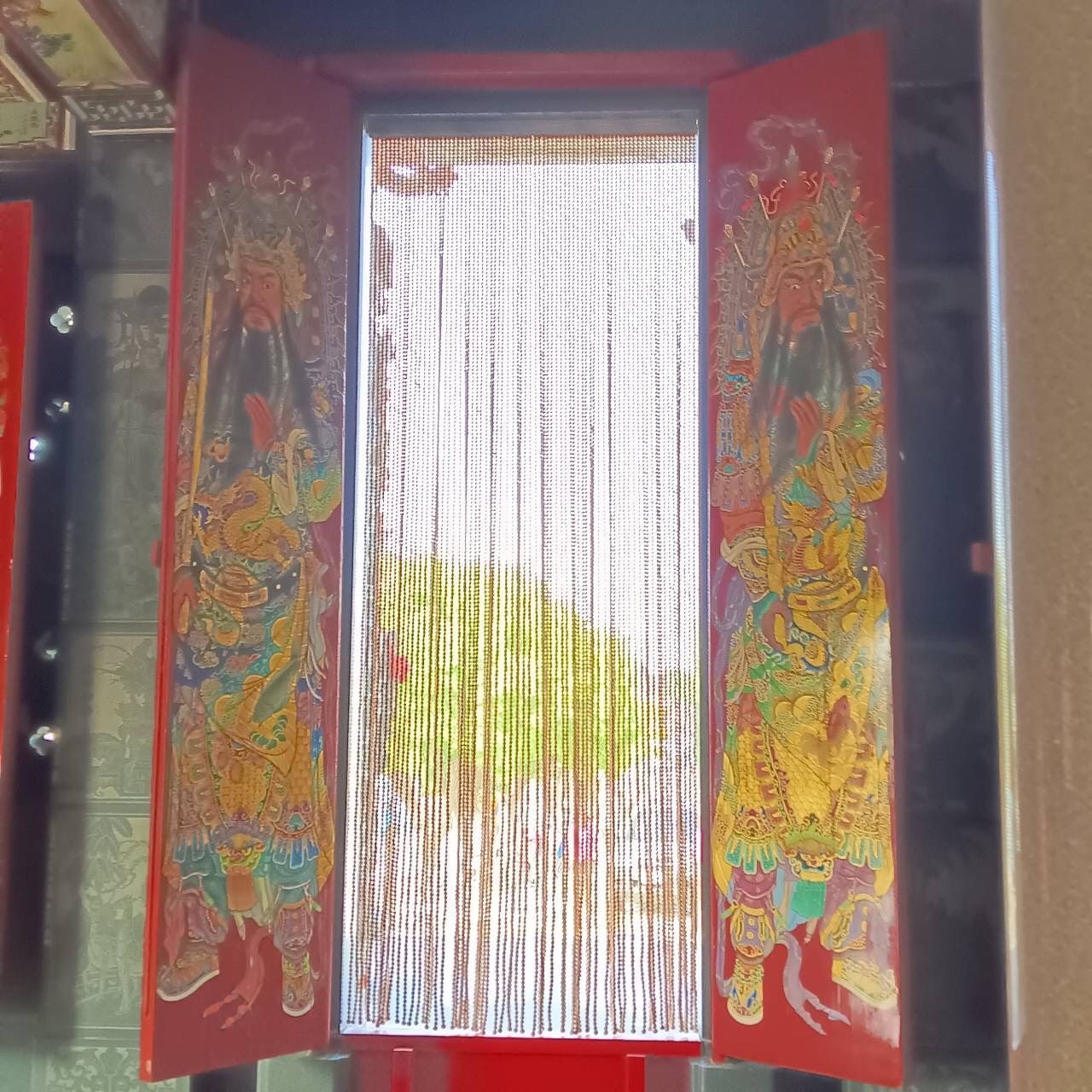 紅色裝飾的寺廟大門打開後,可以看到外面掛著珠簾,還有一棵樹。