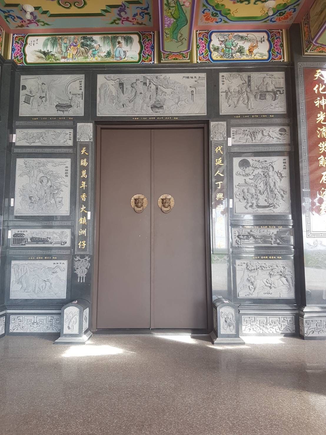 華麗的寺廟入口,灰色雕花牆壁,緊閉的雙扇木門,配有金色把手。