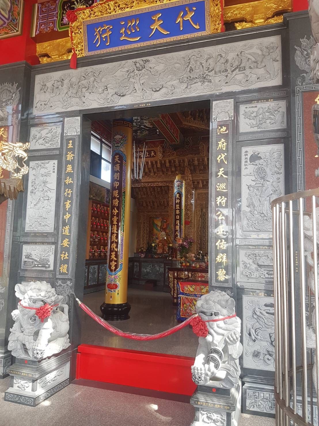 寺廟入口處有華麗的灰色石門、紅色地毯和金色的內部祭壇裝飾。