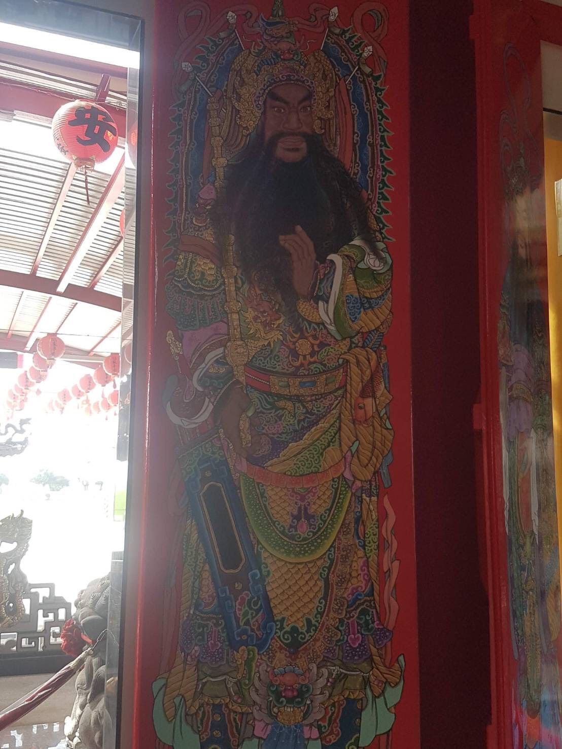 一幅豎幅壁畫,描繪了一位身著華麗長袍、蓄著鬍鬚的神祇,周圍環繞著紅色的寺廟牆壁和懸掛的裝飾品。
