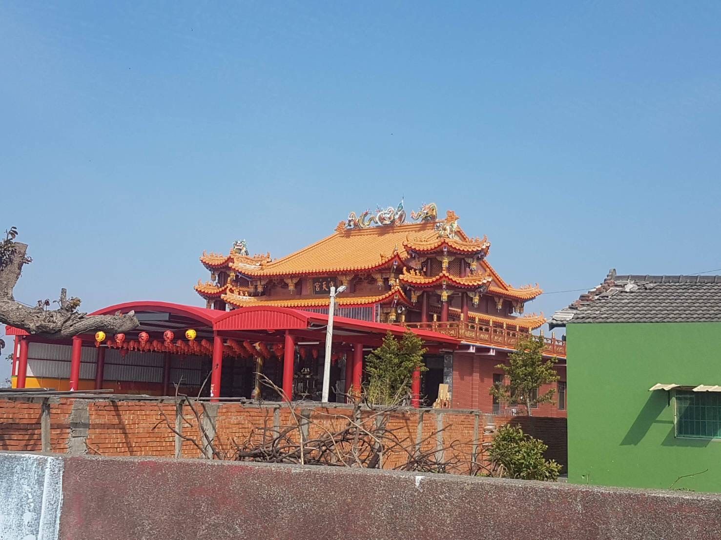 在湛藍的天空下,一座傳統的中國寺廟,有著華麗的金色屋頂和紅色的柱子。