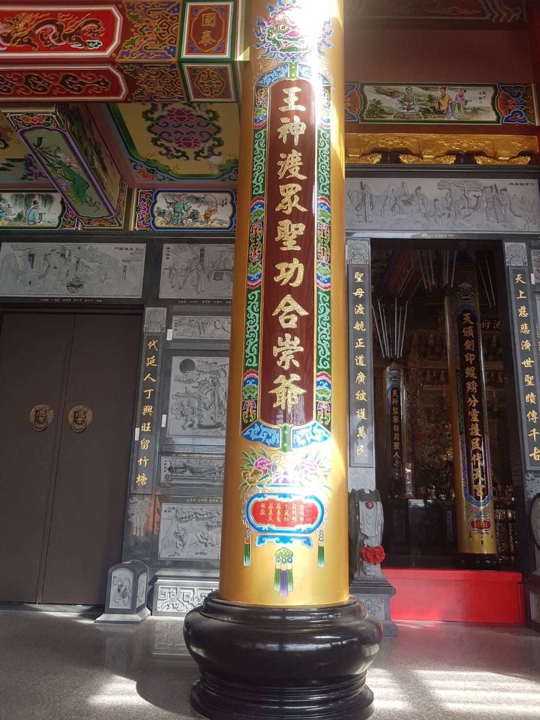 寺廟入口處矗立著一根刻有漢字的金色柱子,天花板裝飾華麗,並設有一扇紅色雙開門。
