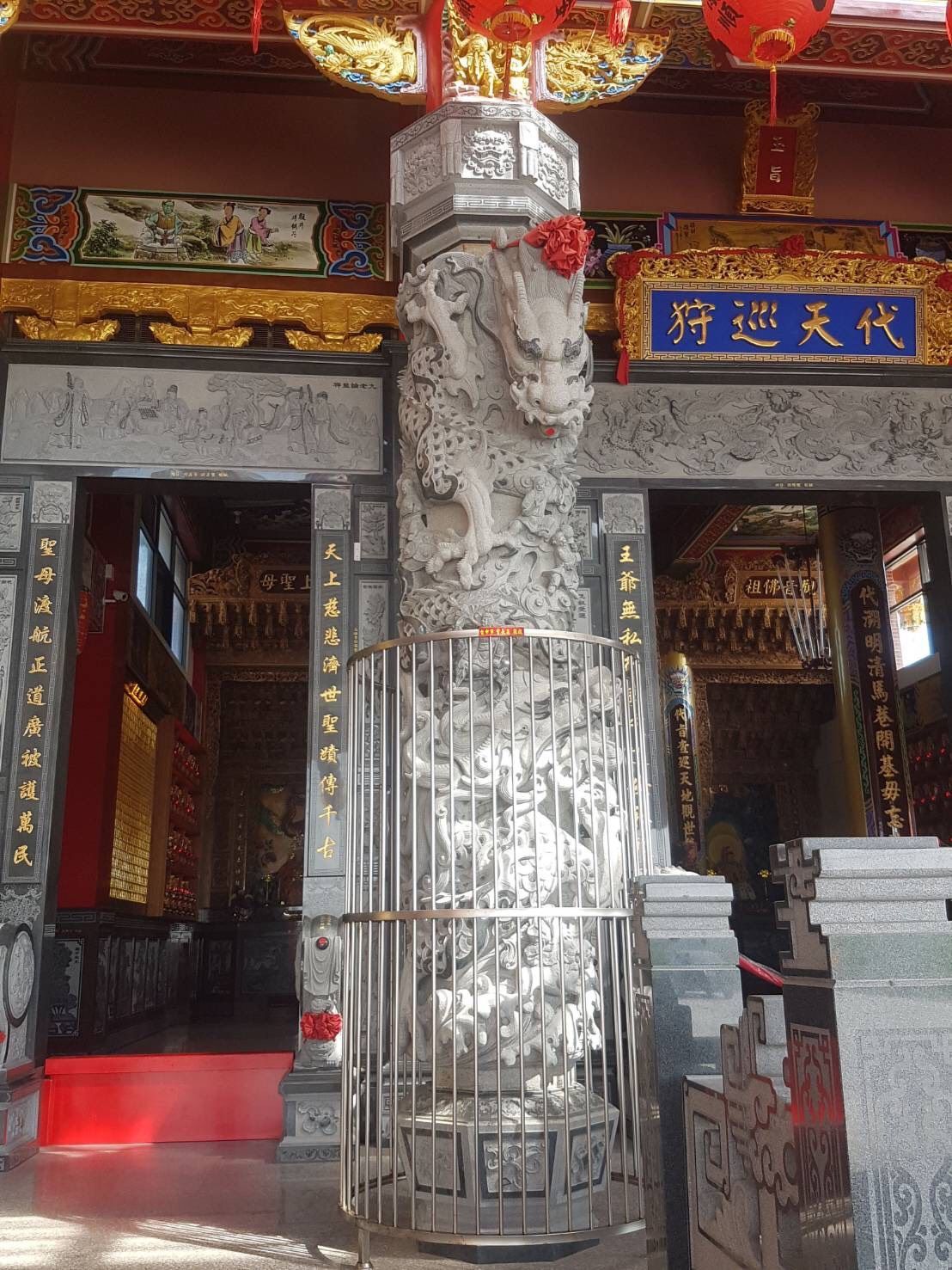華麗的寺廟入口,有雕刻精美的石柱、紅色的柱子和藍金相間的招牌。