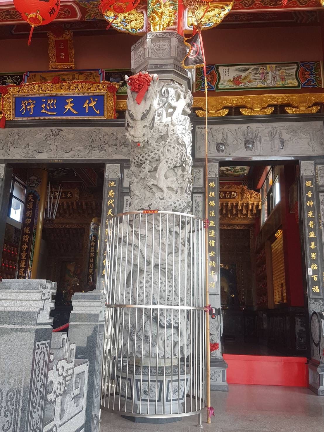 寺廟內部有紅色的柱子、中央的石柱,入口上方有華麗的中國式裝飾。
