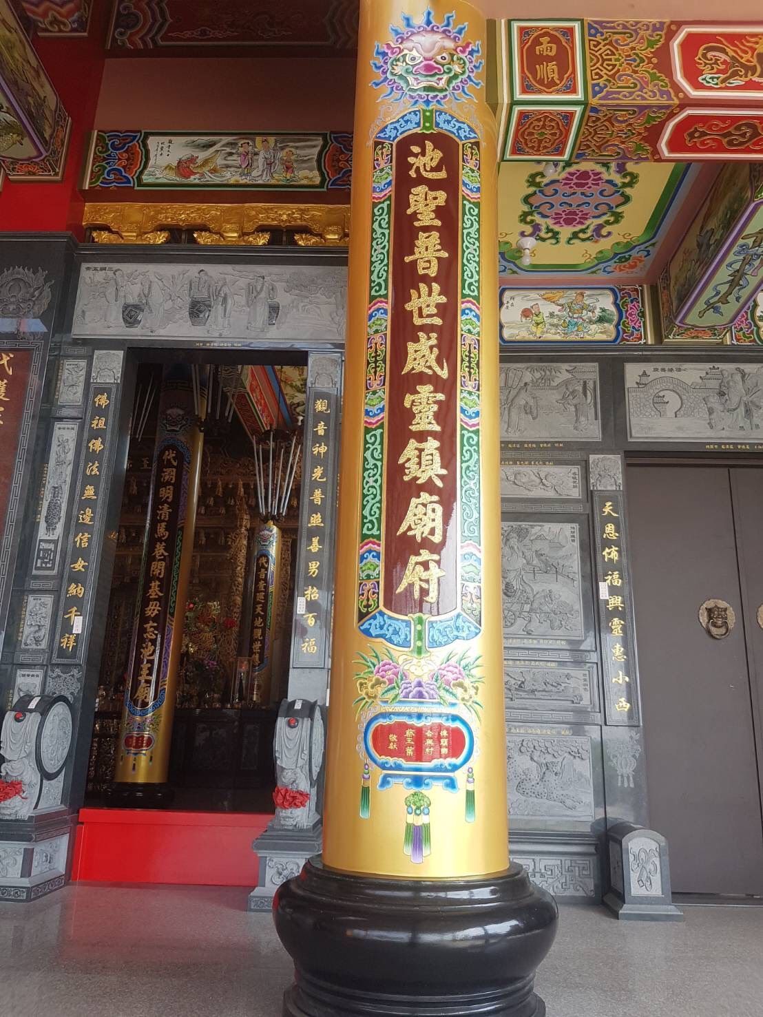 寺廟入口處有華麗的紅金相間柱子、雕花門和色彩繽紛的天花板裝飾。
