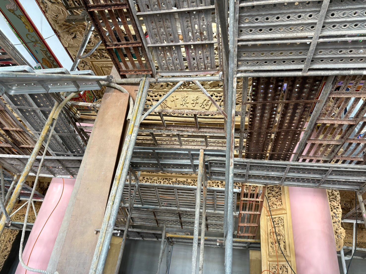 建築工地內部,可見金屬鷹架、橫樑和粉紅色泡沫保溫板。